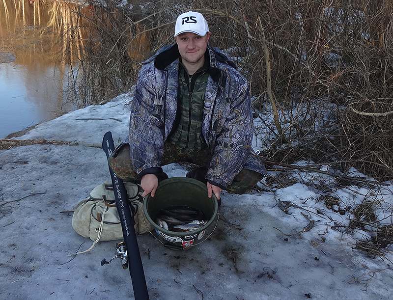 Рыбак держит ведро с рыбой 