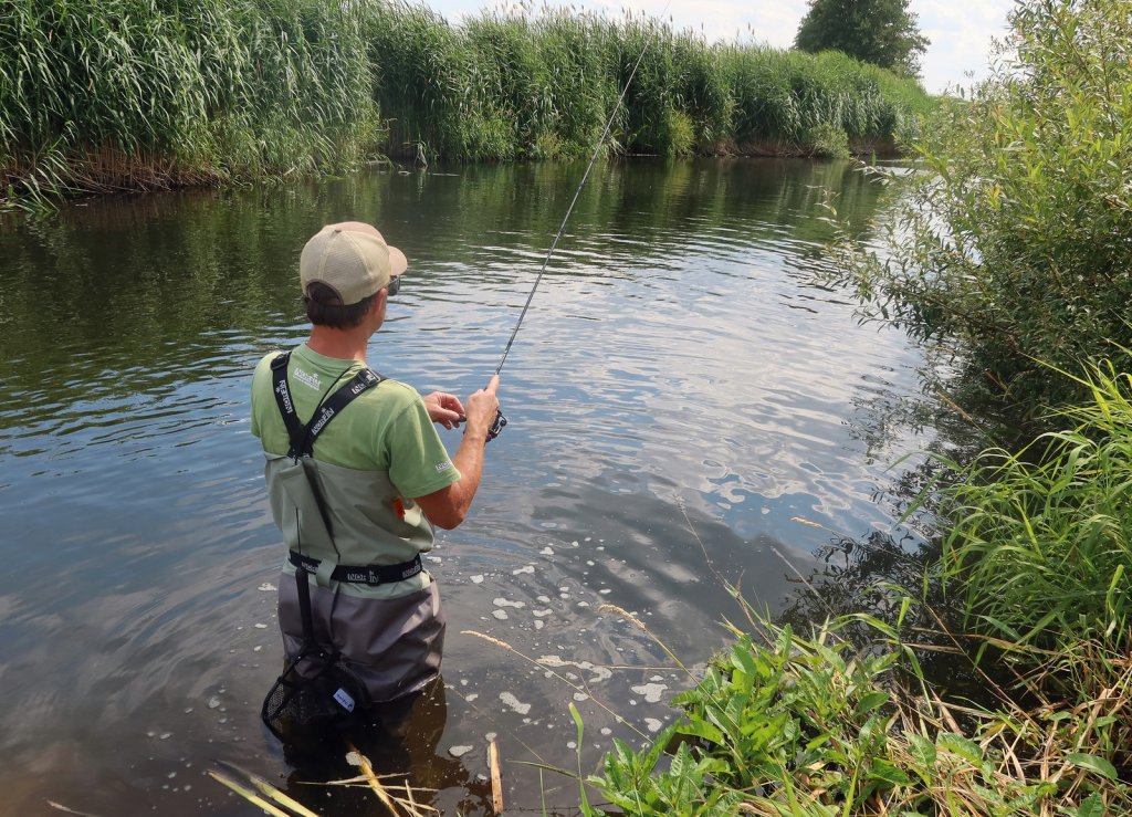 Спиннингист ловит взабродку на реке