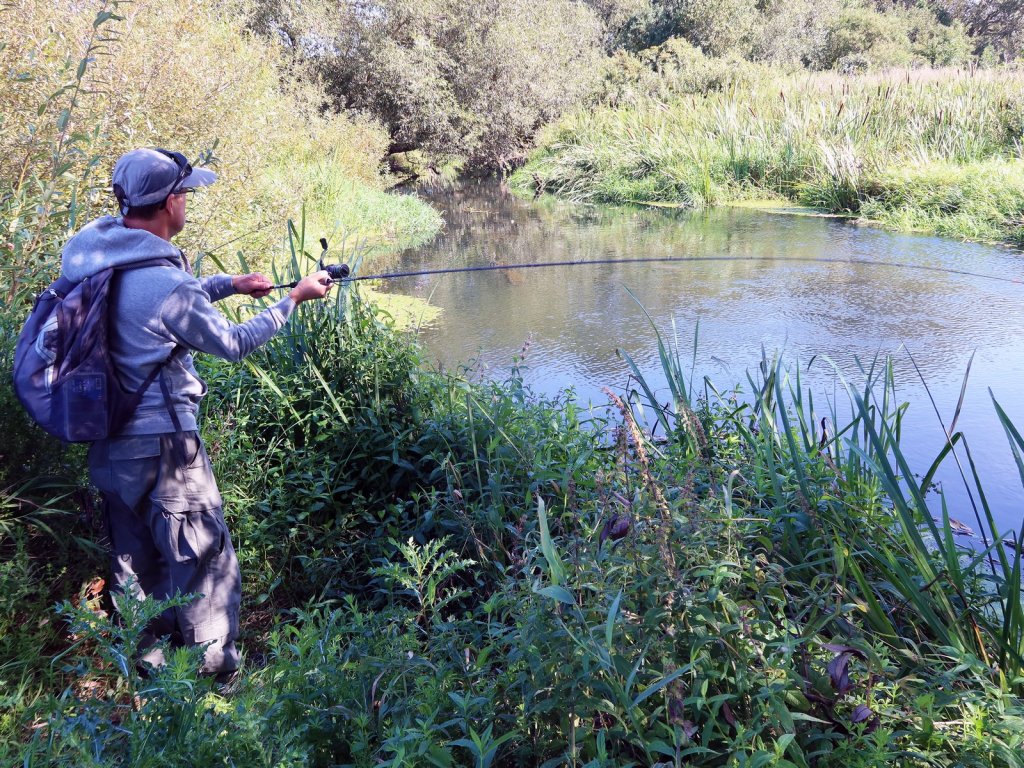 Спиннингист делает заброс на малой реке