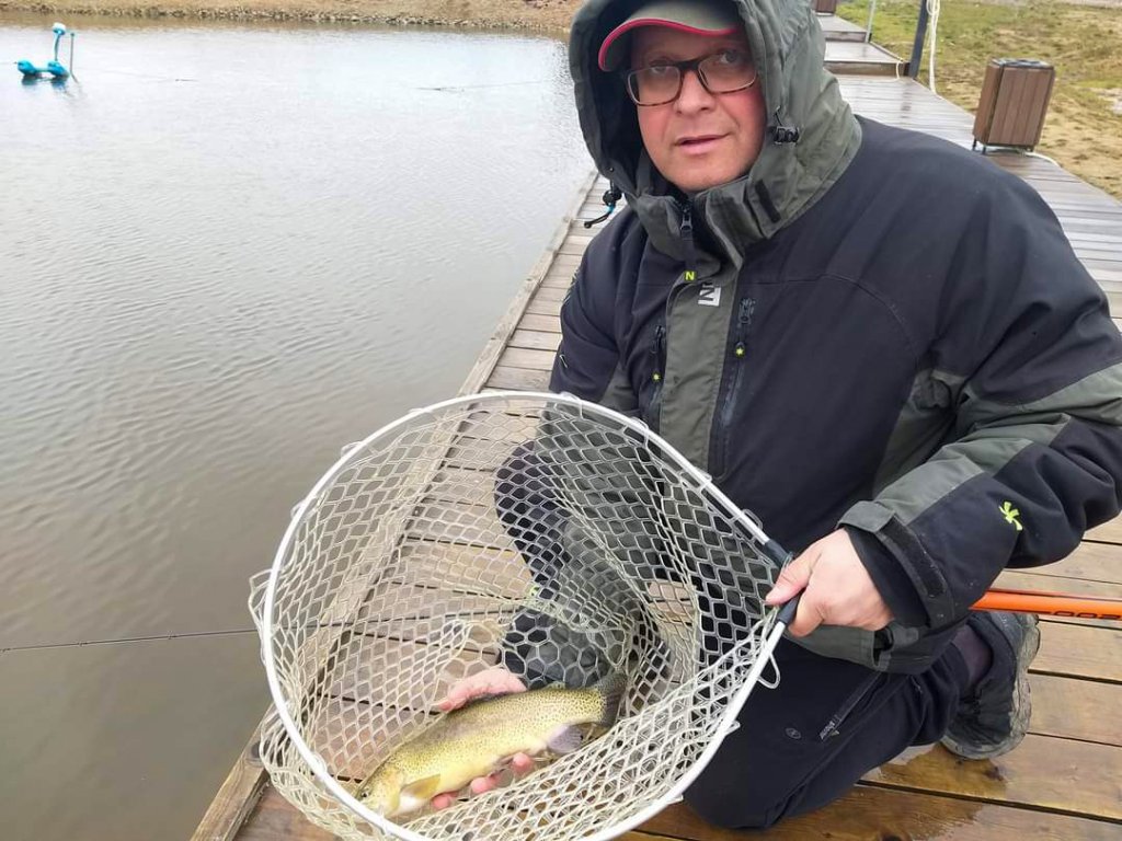 Рыбаr держит форель в силиконовом подсаке Рыбаr держит форель в силиконовом подсаке