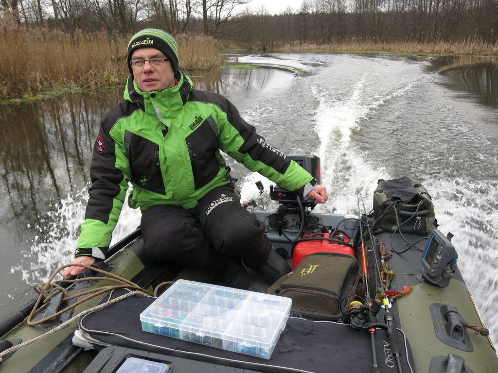 Спиннингист плывёт по реке на моторной лодке