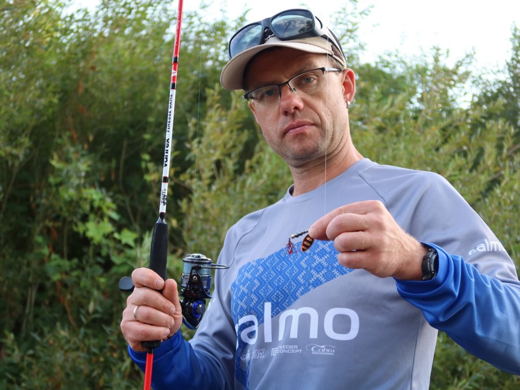 Рыболов показывает вращающуюся блесну, на которую ловит