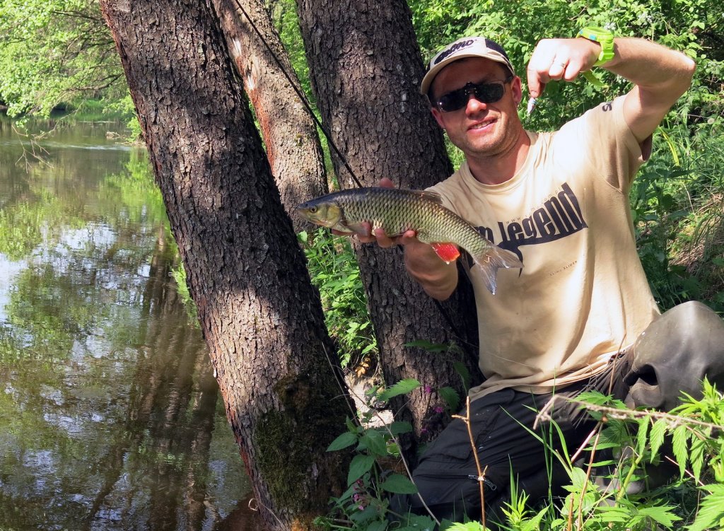 Рыболов показывает голавля и приманку