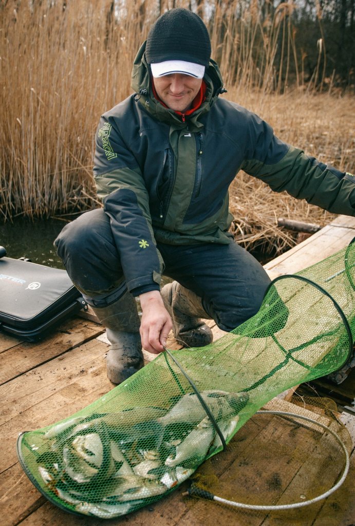 Рыболов с фидерным уловом ранней весной Рыболов с фидерным уловом ранней весной