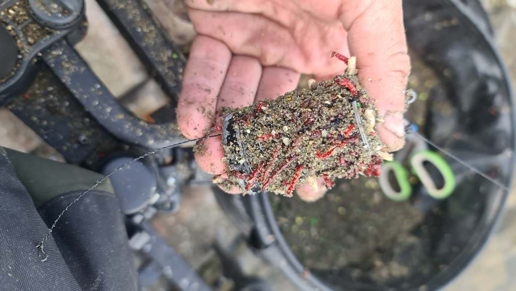 Фидерная кормушка заполненная кормом лежит на руке