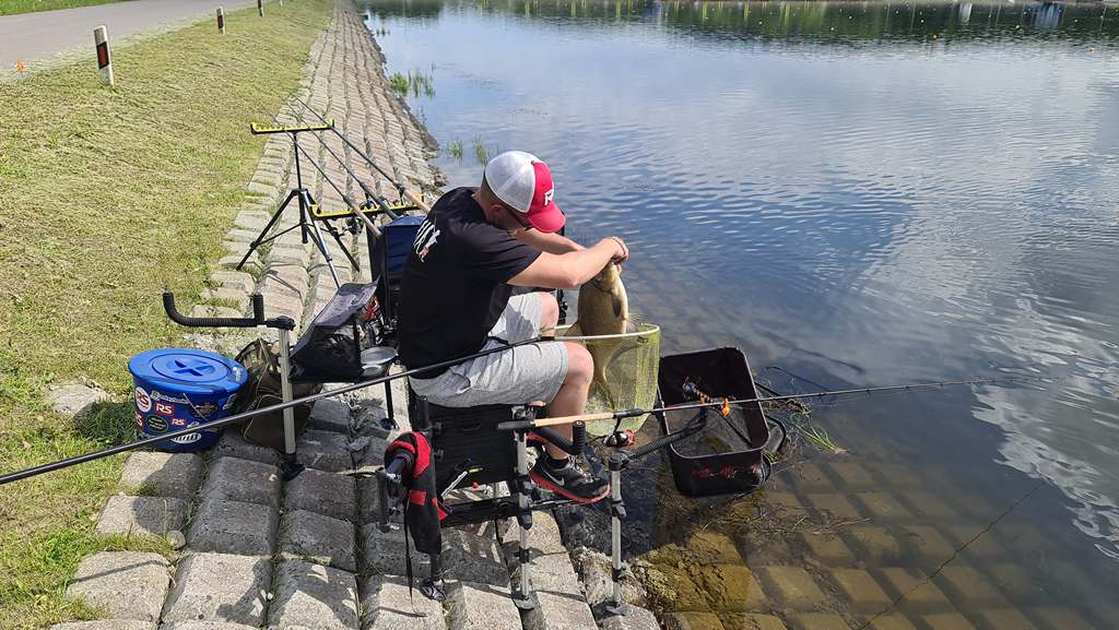 Рыбак достает леща из подсачека
