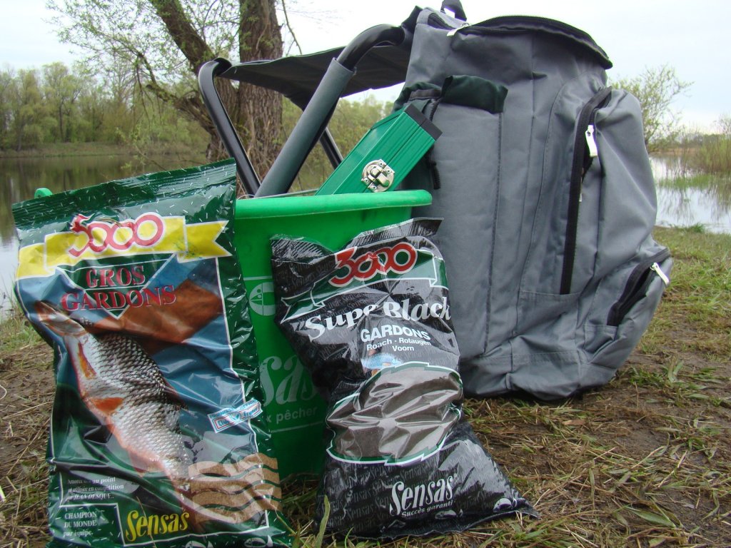 Прикормка Sensas и рюкзак на берегу
