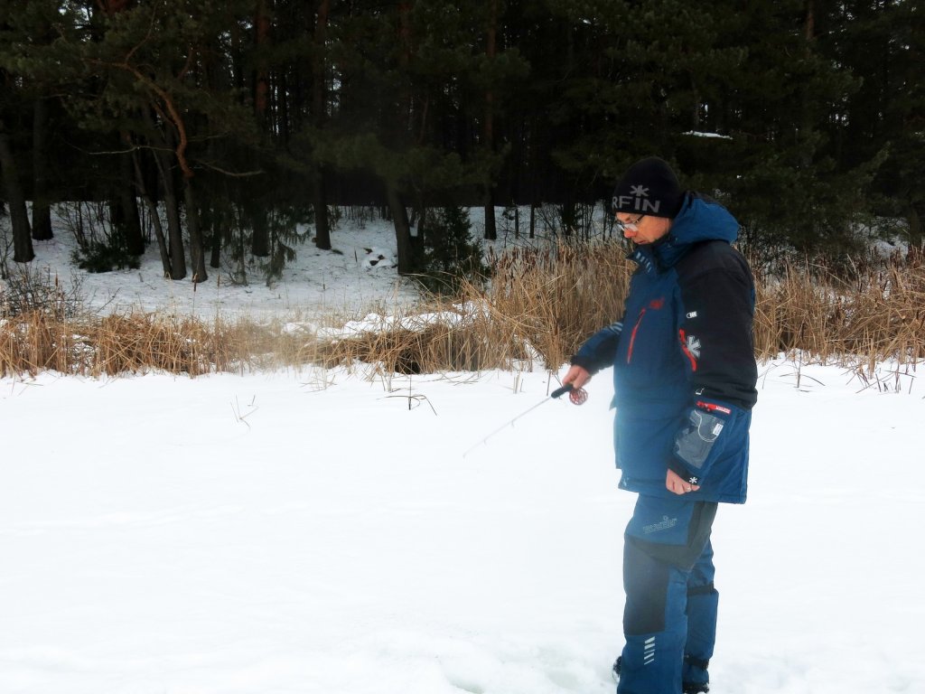 Рыболов ловит зимой у берега