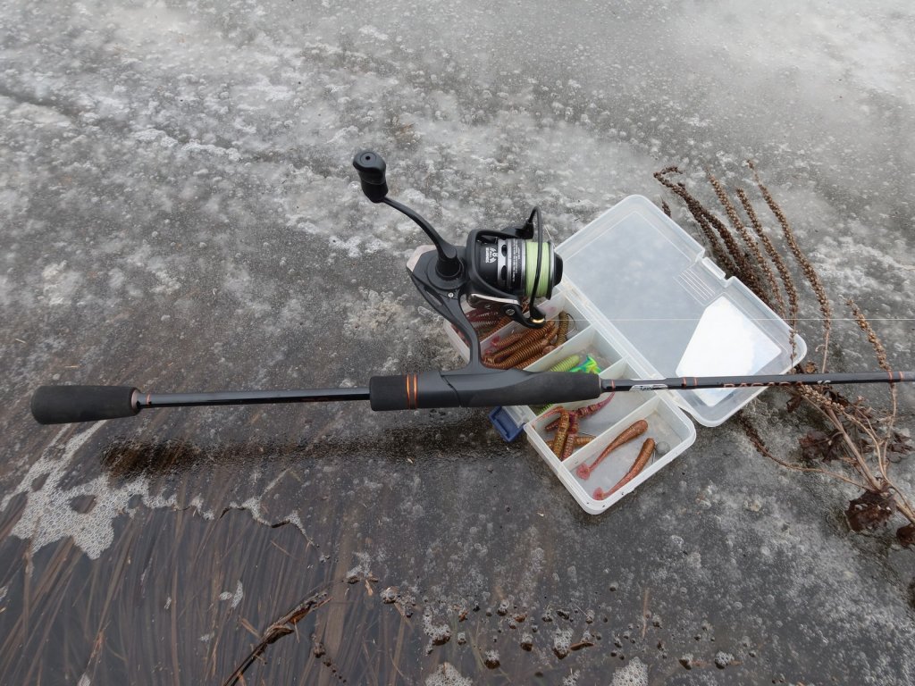 Спиннинг и коробка с приманками на льду
