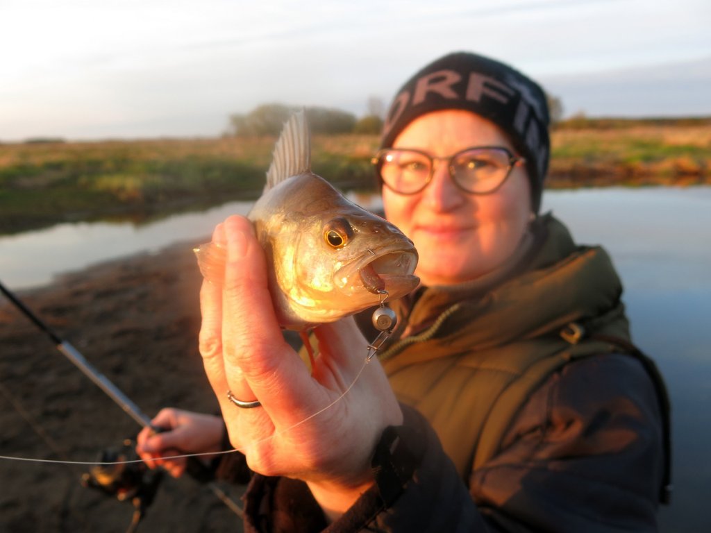 Рыбачка показывает пойманного окуня
