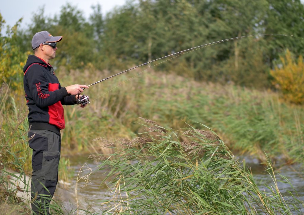 Рыболов ловит спиннингом с берега