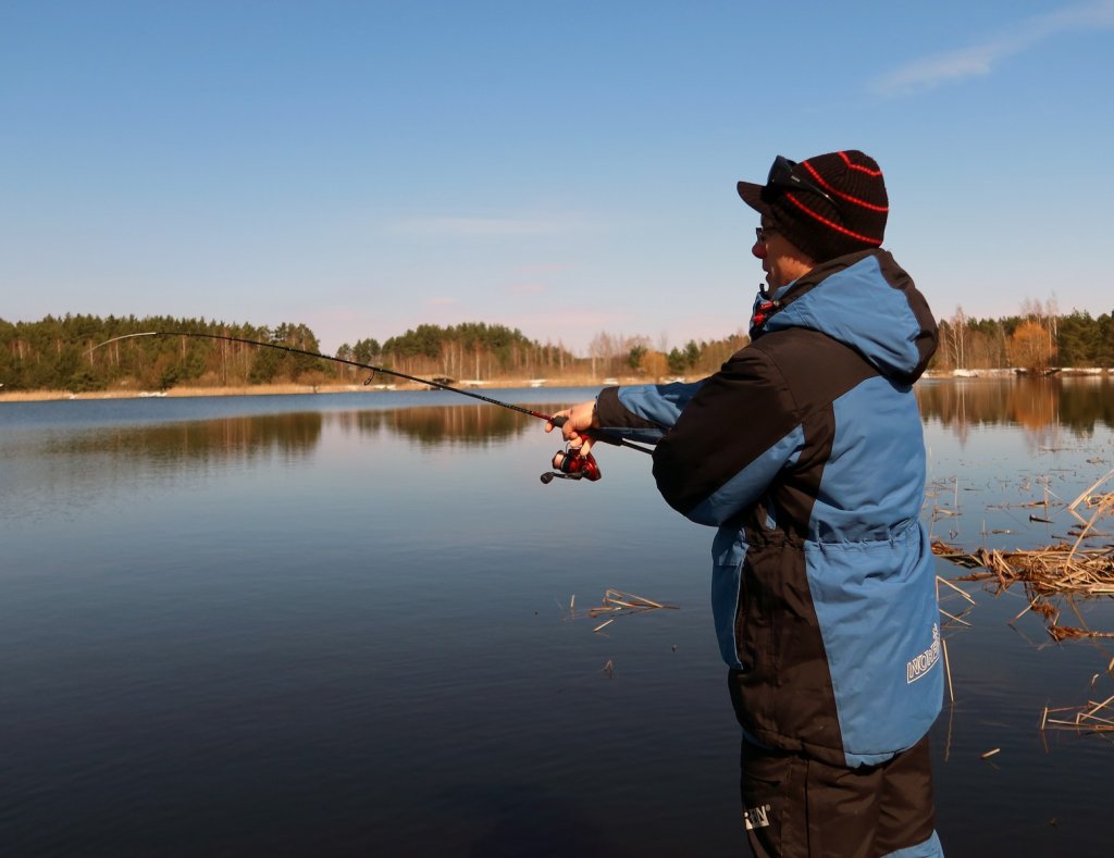 Рыболов ловит лёгким спиннингом на пруду весной