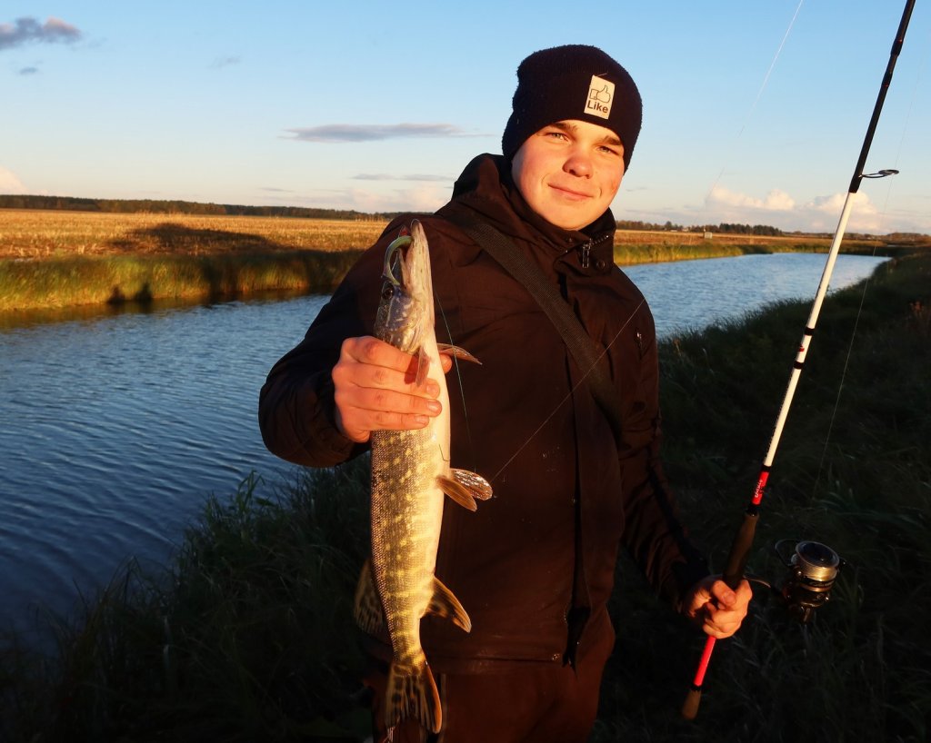 Юный спиннингист со щукой на канале осенью