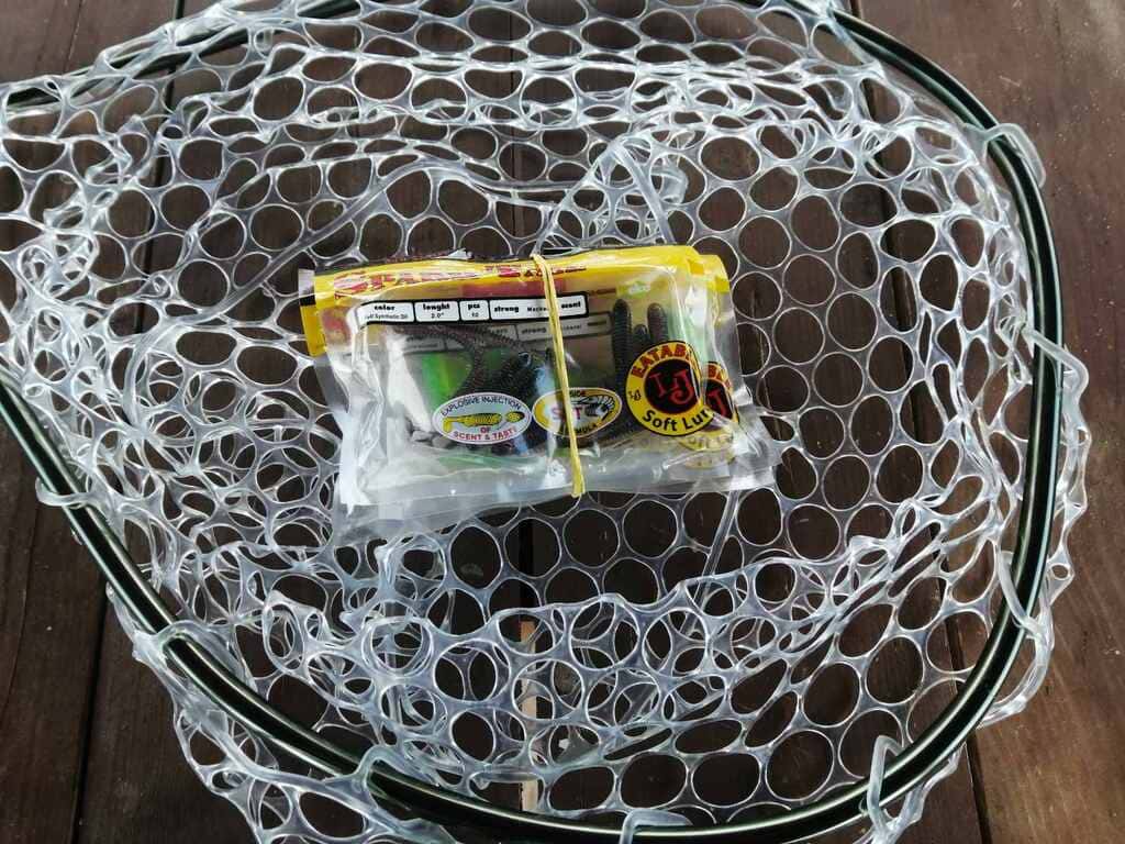 Несколько искусственных приманок разных типов лежат в сетчатом подсачеке 