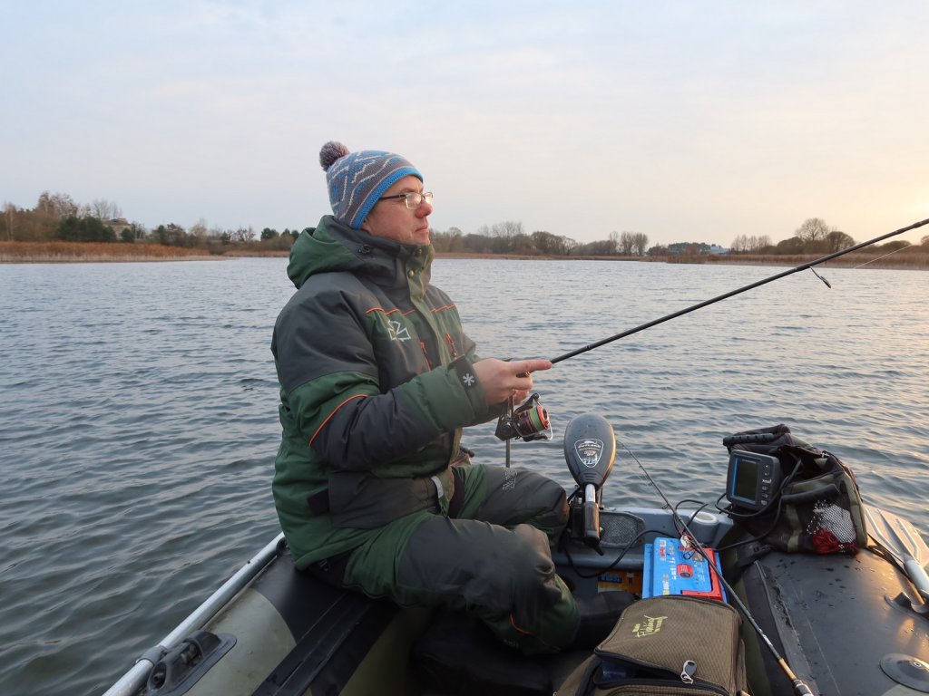 Спиннингист делает проводку, сидя в лодке