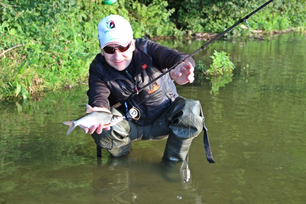 Рыболов с фидерной снастью и рыбой