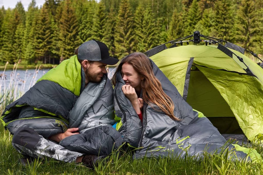 Парень и девушка укутываются в спальный мешок одеяло Norfin