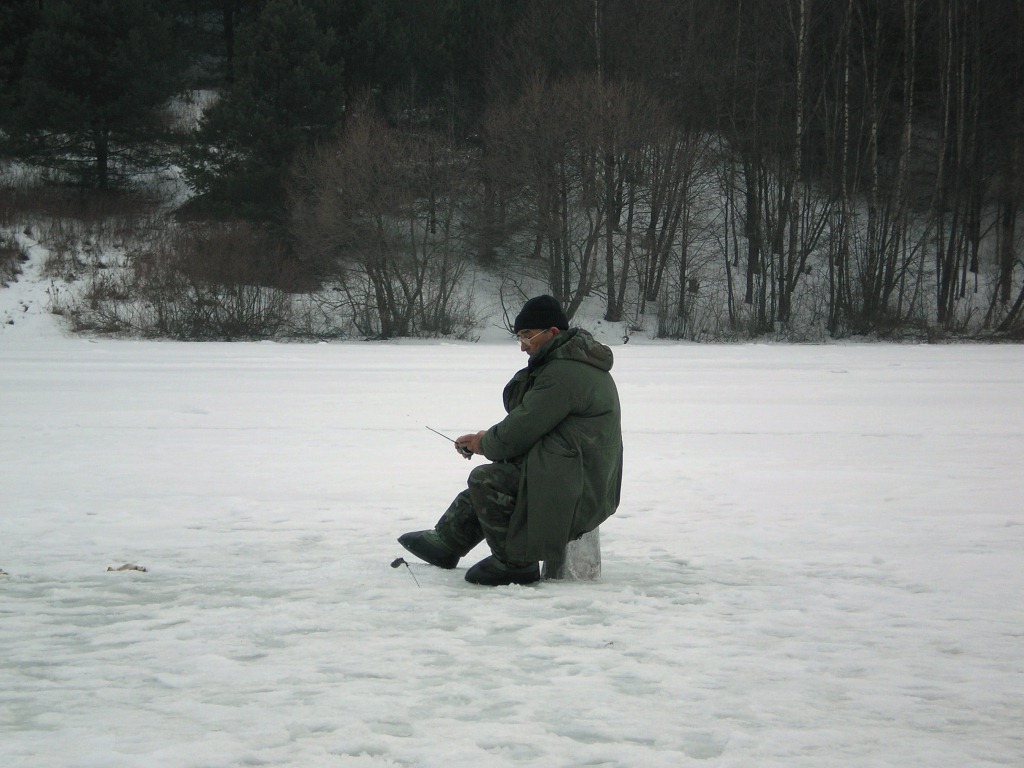 Рыбак ловит со льда на чертика