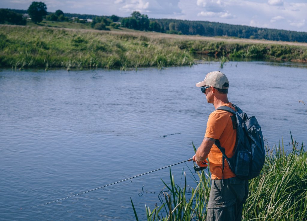 Рыболов делает проводку спиннингом на реке