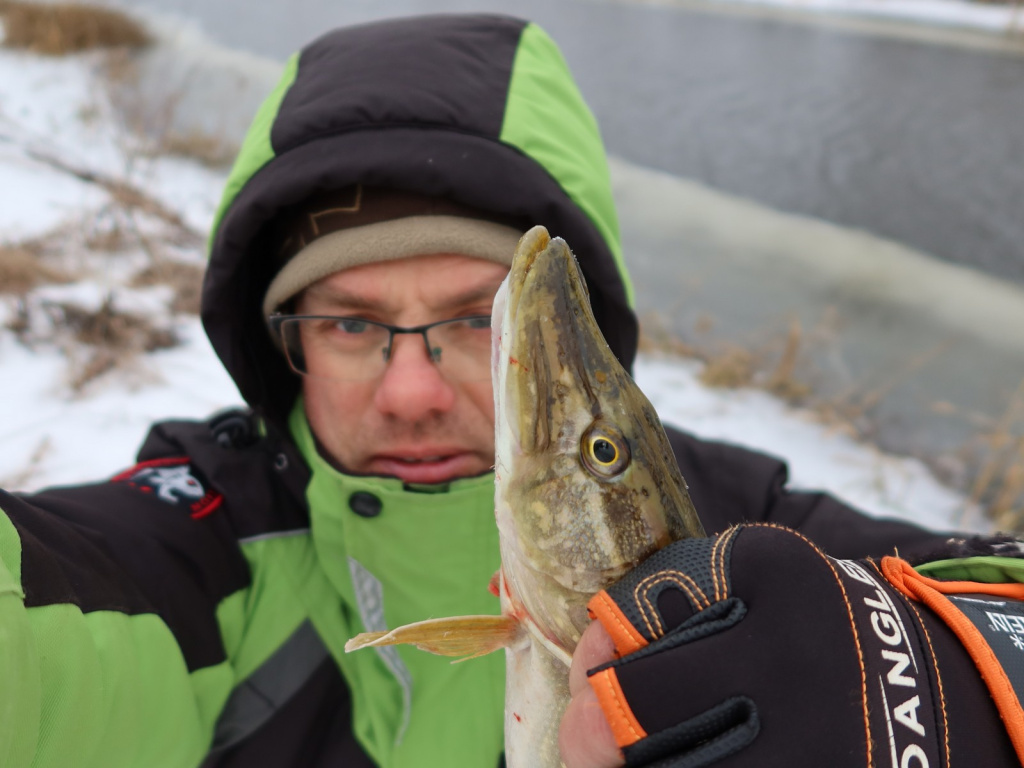 Рыбак зимой со щукой выловленной спиннингом