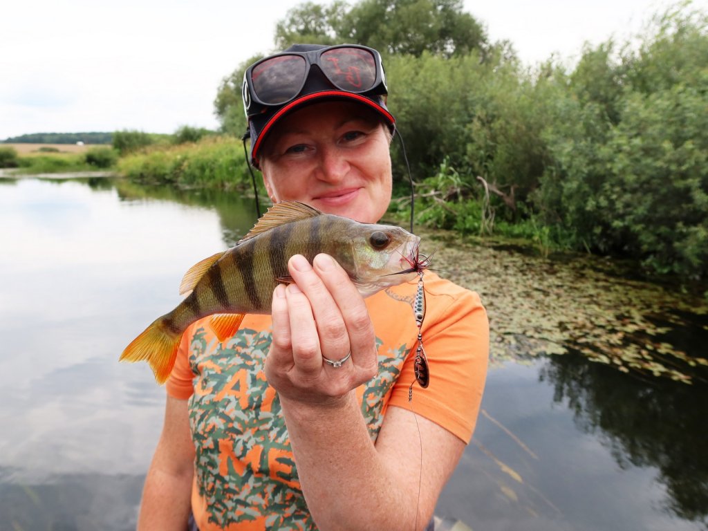 Довольная рыбачка с окунем на речке Довольная рыбачка с окунем на речке