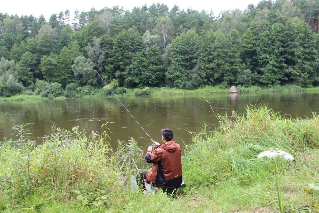 Рыболов ловит фидером на речном перекате