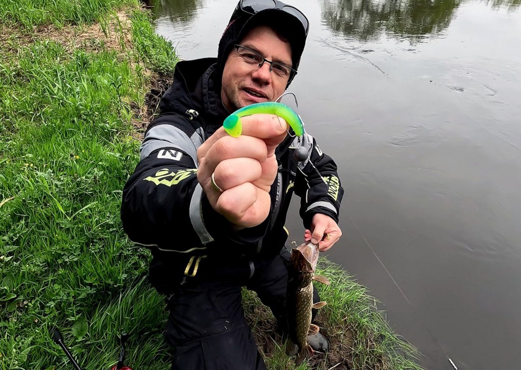 Рыболов показывает приманку на офсетном крючке, на которую поймал щуку Рыболов показывает приманку на офсетном крючке, на которую поймал щуку