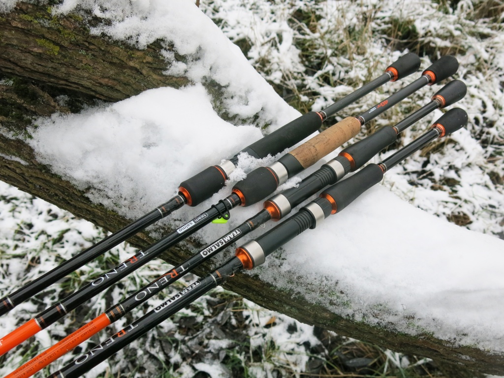 Четыре спиннинга Salmo Treno лежат на заснеженном стволе дерева