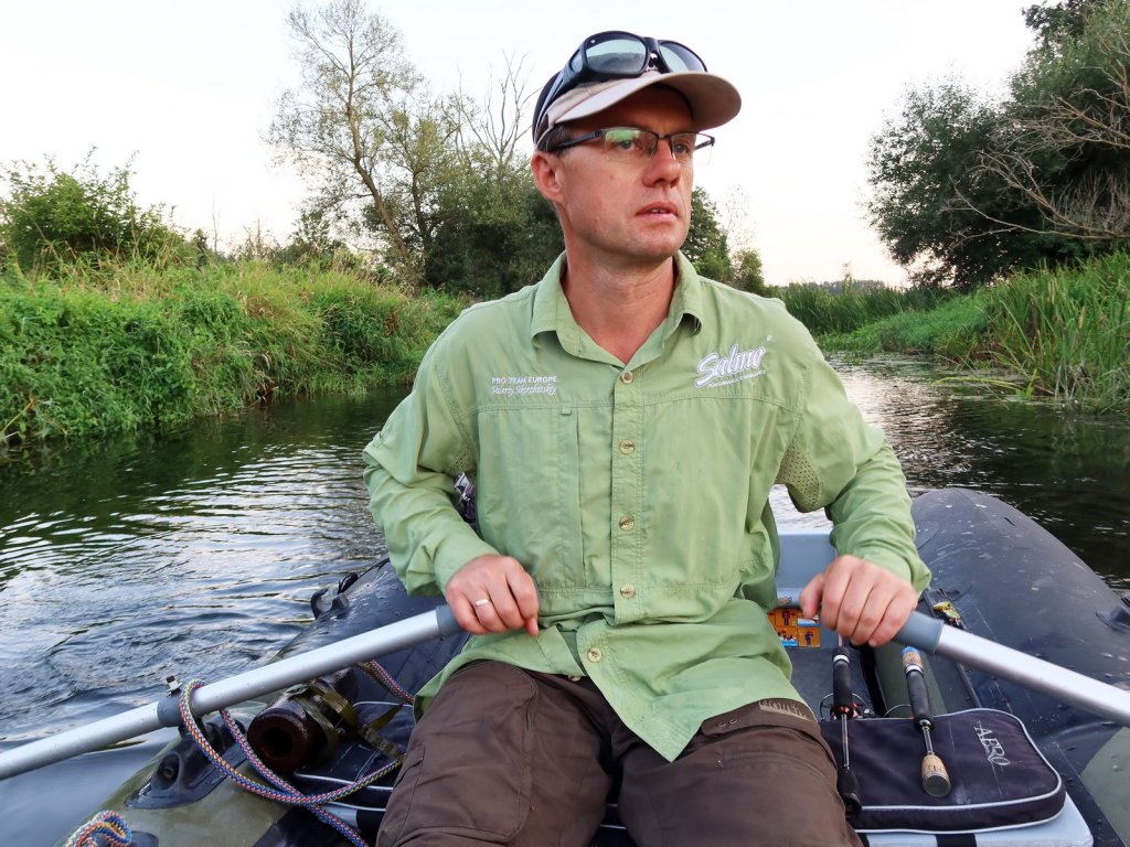 Рыболов плывёт на лодке по малой реке