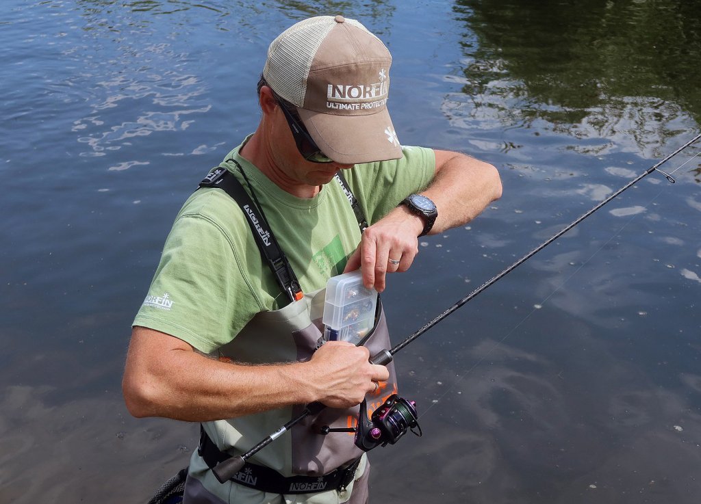 Рыболов кладёт в карман коробку с приманками