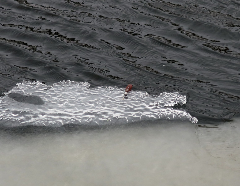 Джиг-головка с приманкой на льду зимой у реки