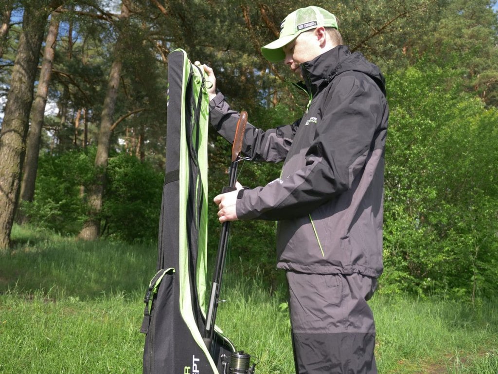 Рыбак достает удилище из чехла для удочек