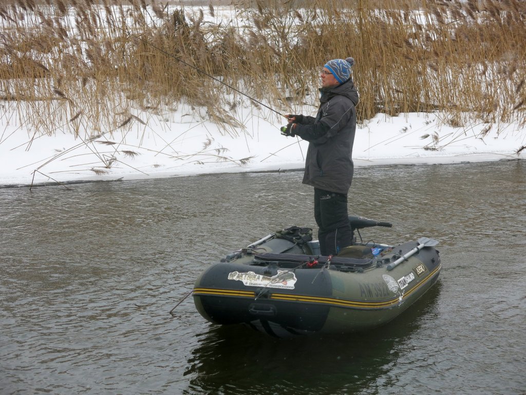 Спиннингист делает проводку на зимней реке