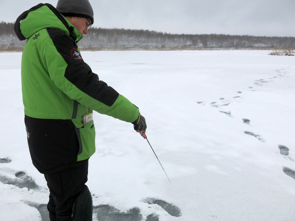 Рыболов блеснит на льду