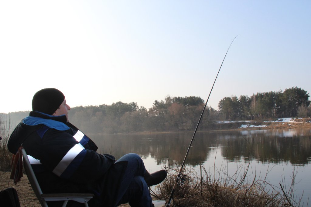 Рыболов ловит на фидер ранней весной на реке