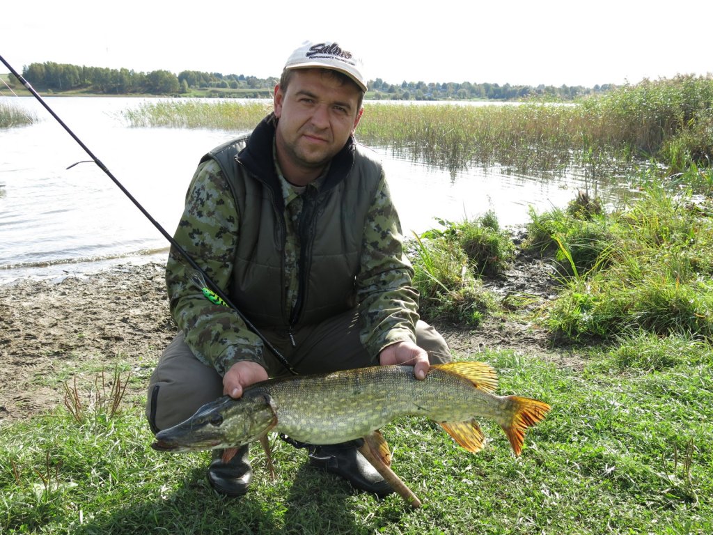 Спиннингист со щукой на берегу Спиннингист со щукой на берегу