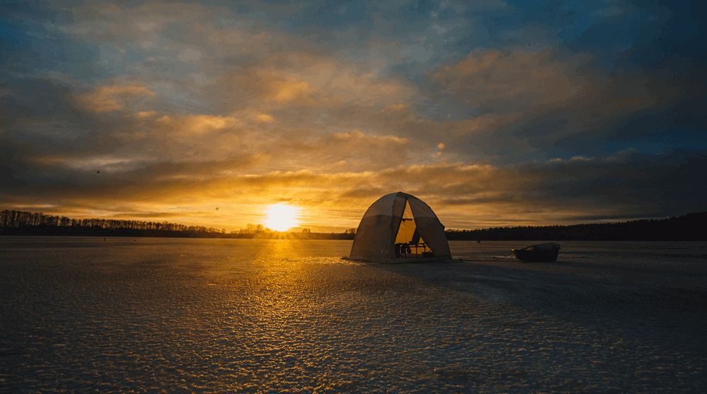 Зимняя рыболовная палатка на фоне заката