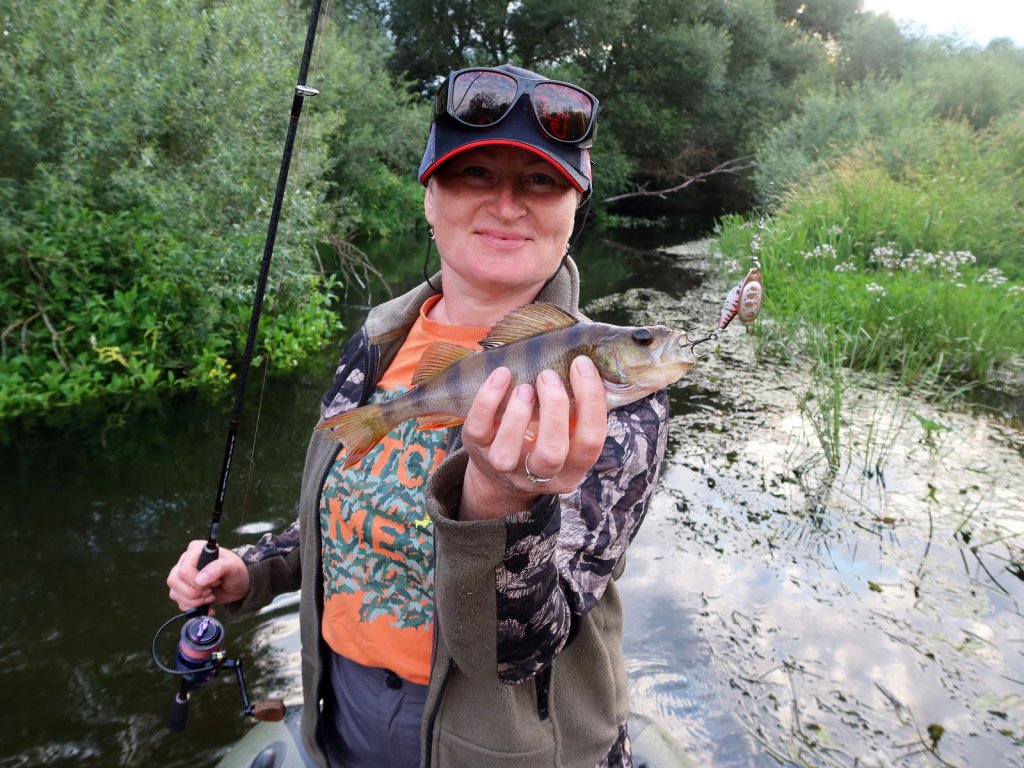 Рыбачка держит окуня, пойманного на вертушку