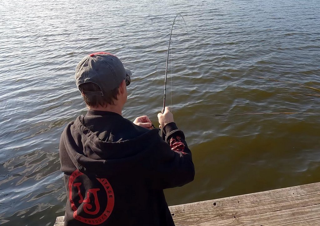 Спиннингист вываживает рыбу Спиннингист вываживает рыбу