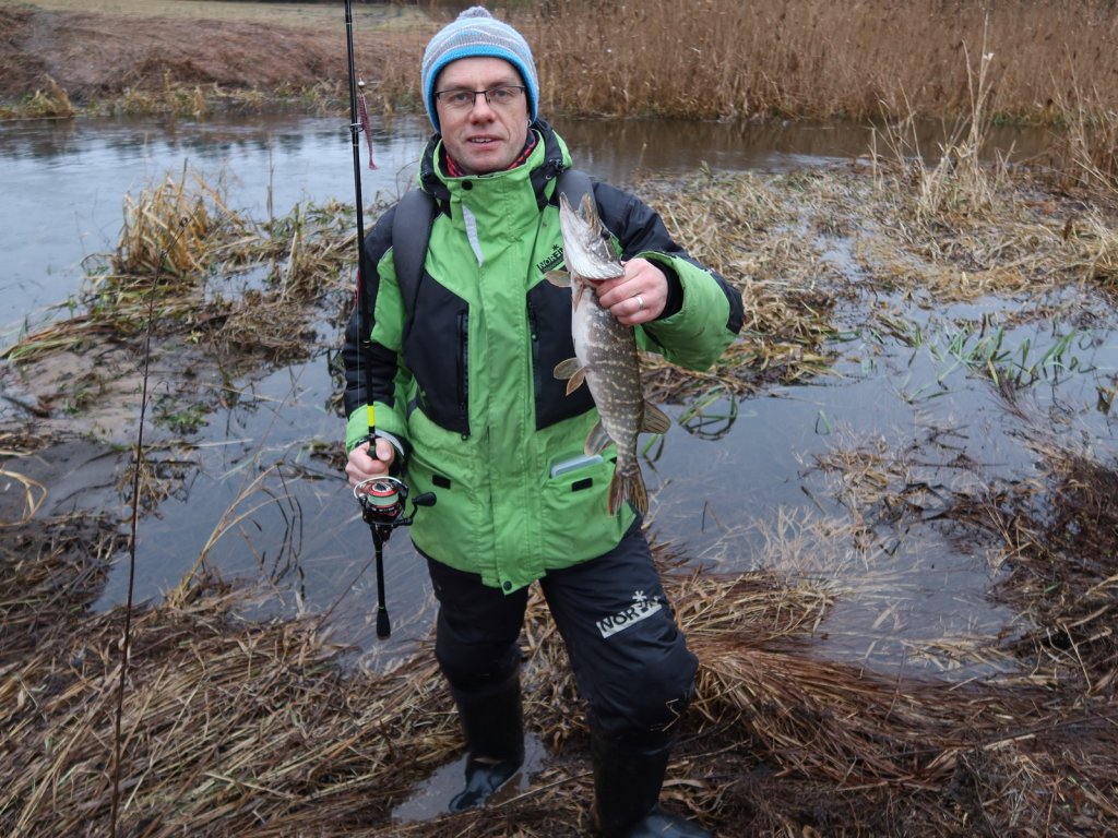Довольный рыболов с небольшой речной щукой