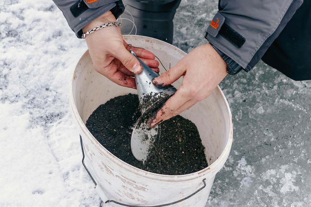 Рыбак забивает кормушку для зимней рыбалки Рыбак забивает кормушку для зимней рыбалки