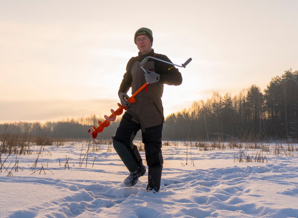 Рыболов с ледобуром на льду