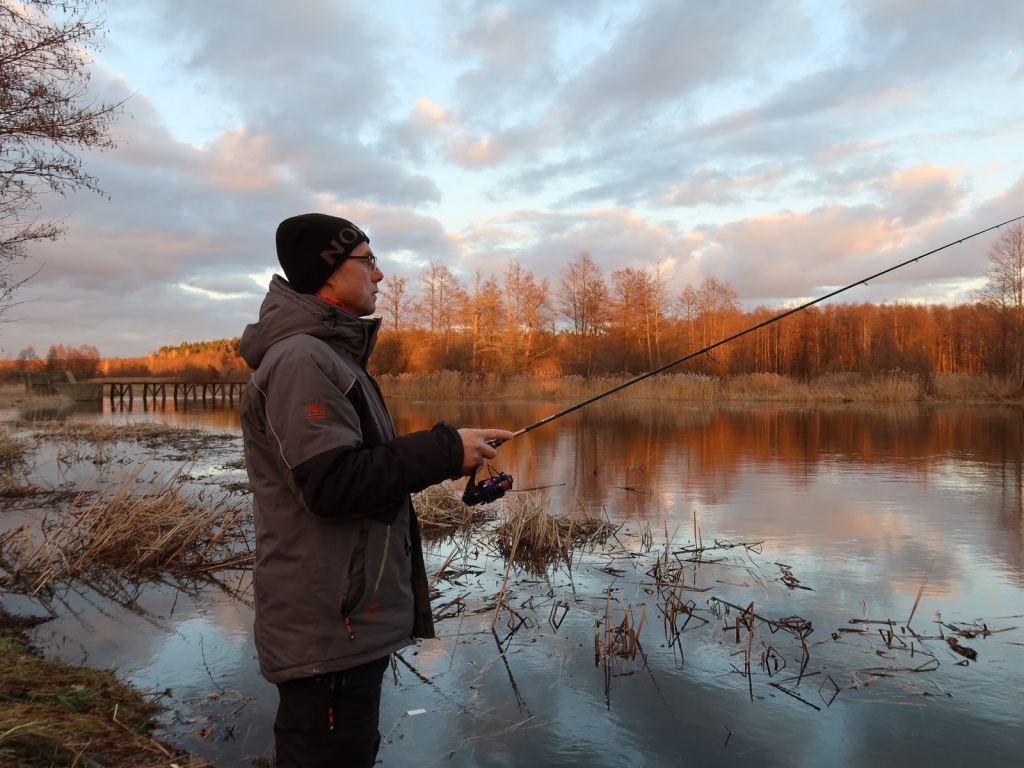 Рыбак ловит спиннингом во время заката на реке
