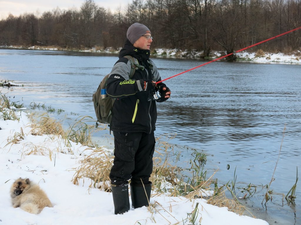 Рыболов ловит спинингом на зимней реке