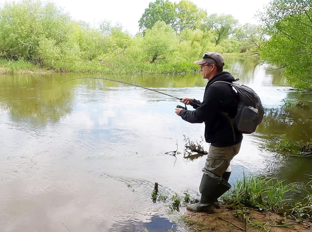 Спиннингист вываживает рыбу Спиннингист вываживает рыбу
