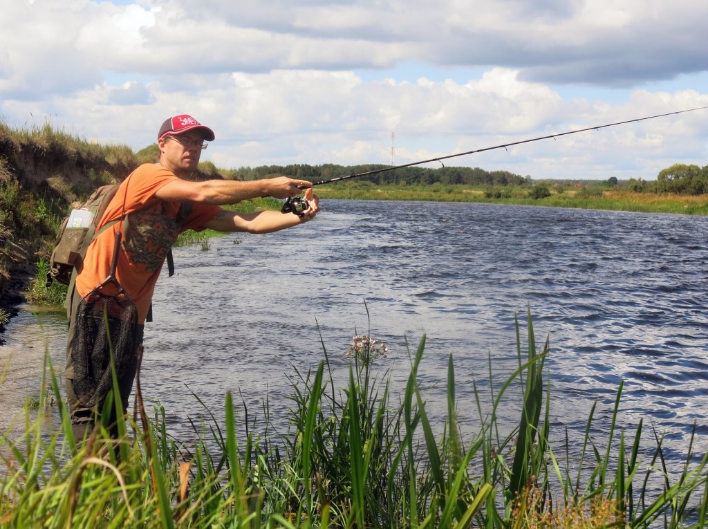 Рыболов ловит спиннингом на реке Рыболов ловит спиннингом на реке